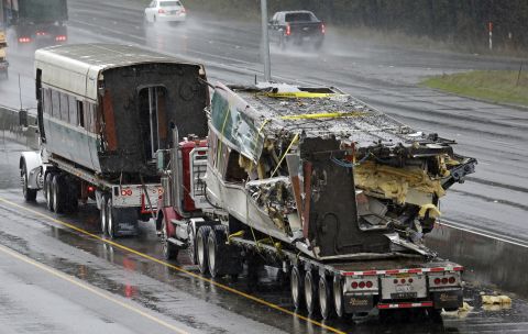 Two damaged train cars sit on flatbed trailers after being taken away from the scene on December 19. When it derailed, the train was going 80 mph in a 30 mph zone. Federal investigators said they don't know why yet.