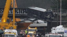 A damaged Amtrak train car is lowered from an overpass at the scene of Monday's deadly train crash onto Interstate 5 Tuesday, Dec. 19, 2017, in DuPont, Wash. Federal investigators say they don't yet know why the Amtrak train was traveling 50 mph over the speed limit when it derailed Monday south of Seattle.  (AP Photo/Elaine Thompson)