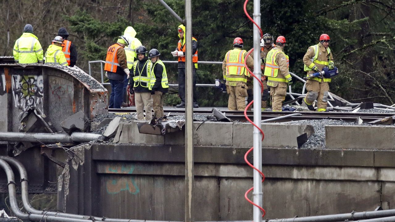 Workers stand atop a damaged railroad bridge at the scene of an Amtrak train crash onto Interstate 5 a day earlier Tuesday, Dec. 19, 2017, in DuPont, Wash. Federal investigators say they don't yet know why the Amtrak train was traveling 50 mph over the speed limit when it derailed Monday south of Seattle.  (AP Photo/Elaine Thompson)