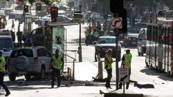 A white SUV (L) sits in the middle of the road as police and emergency personnel work at the scene of where a car ran over pedestrians in Flinders Street in Melbourne on December 21, 2017.
The car ploughed into a crowd in Australia's second-largest city on December 21, injuring at least a dozen people, some of them seriously, officials said. / AFP PHOTO / Mark Peterson        (Photo credit should read MARK PETERSON/AFP/Getty Images)