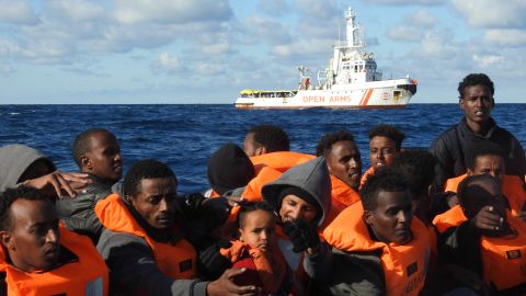 Rescued migrants wait to board the Open Arms. 
