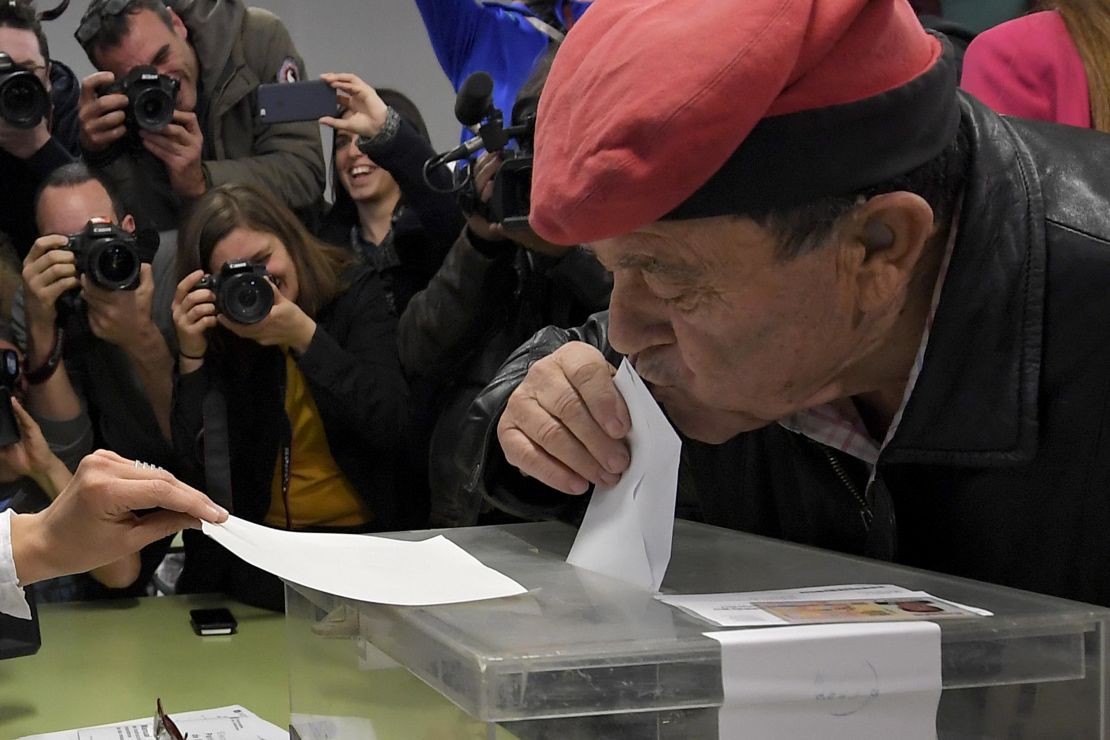 A man wearing a traditional Catalan barretina hat kisses his ballot before voting in Barcelona.