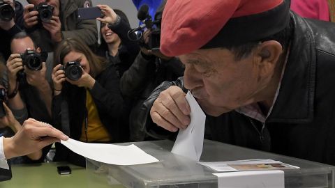 A man wearing a traditional Catalan barretina hat kisses his ballot before voting in Barcelona.