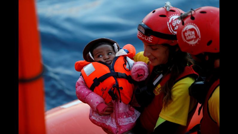 A crew member of MV Open Arms, the search and rescue ship of Proactiva Open Arms, carries a migrant baby during a mid-sea transfer of migrants in the central Mediterranean, off the coast of Libya, on Saturday, December 16. The baby was being passed to crew members of MV Aquarius, a search and rescue ship run in partnership between SOS Mediterranee and Médecins Sans Frontières.
