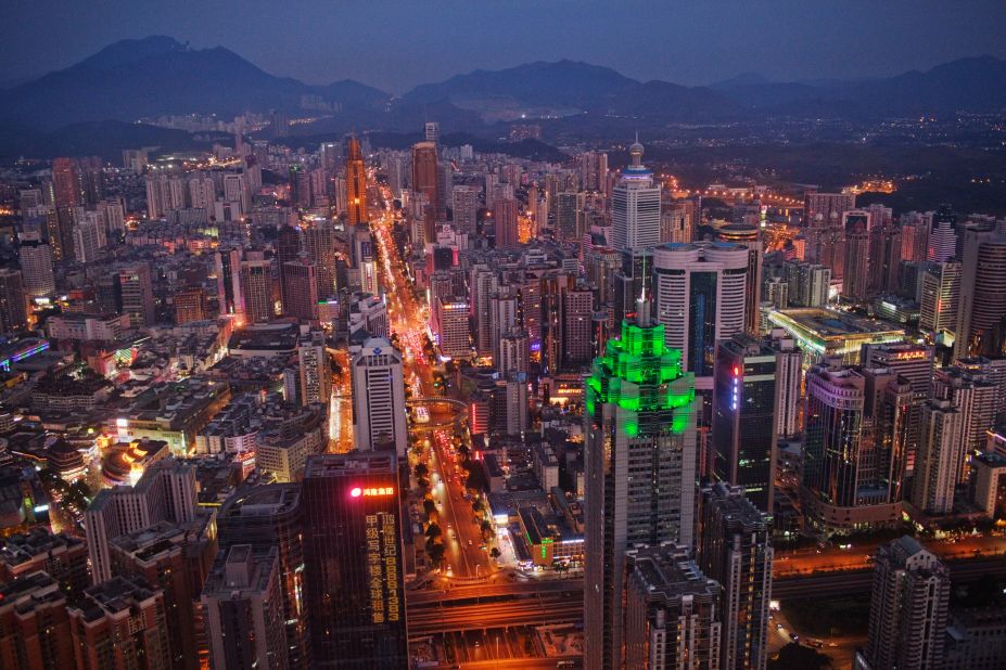 The Shenzhen skyline, including The Shenzhen World Financial Center, illuminated by green lights, stretches into the distance.