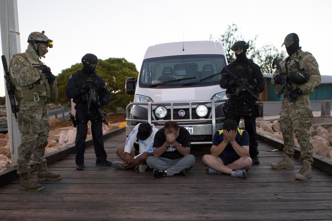 Three of the drug suspects, guarded by AFP officers, next to the van into which the drugs were loaded.