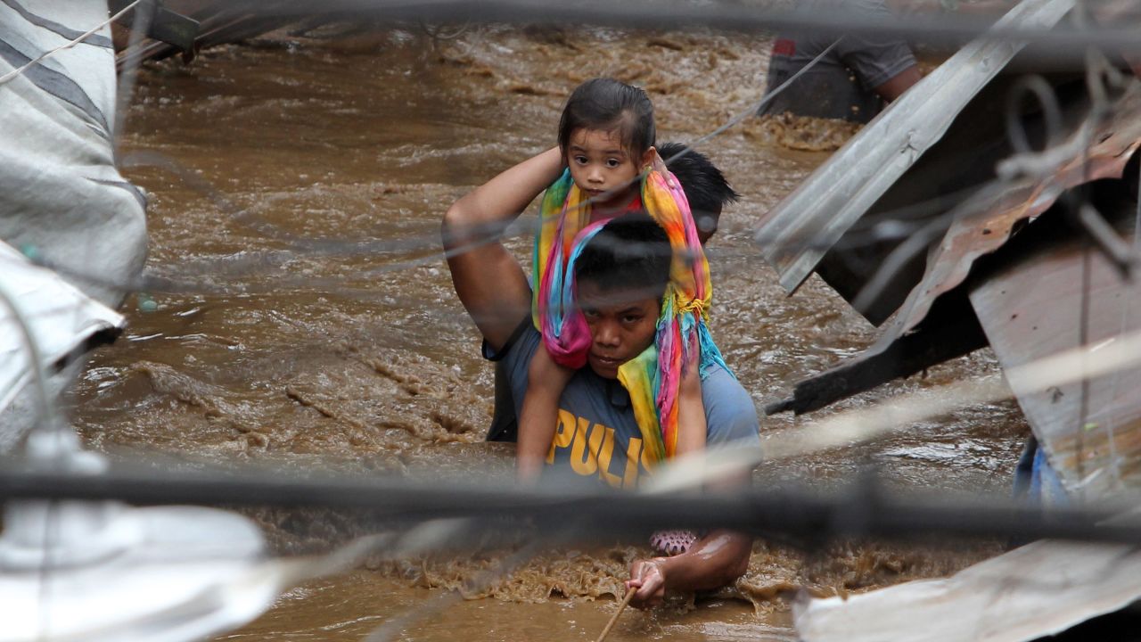 A police officer carries a young girl on a flooded street in Cagayan de Oro on Friday, December 22. 