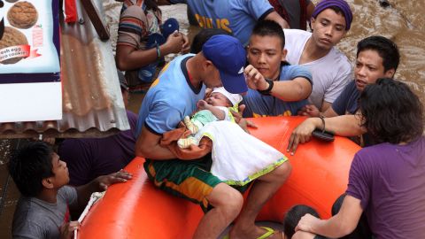 Police evacuate a baby in Cagayan de Oro on December 22 after heavy rains resulting from Tembin.