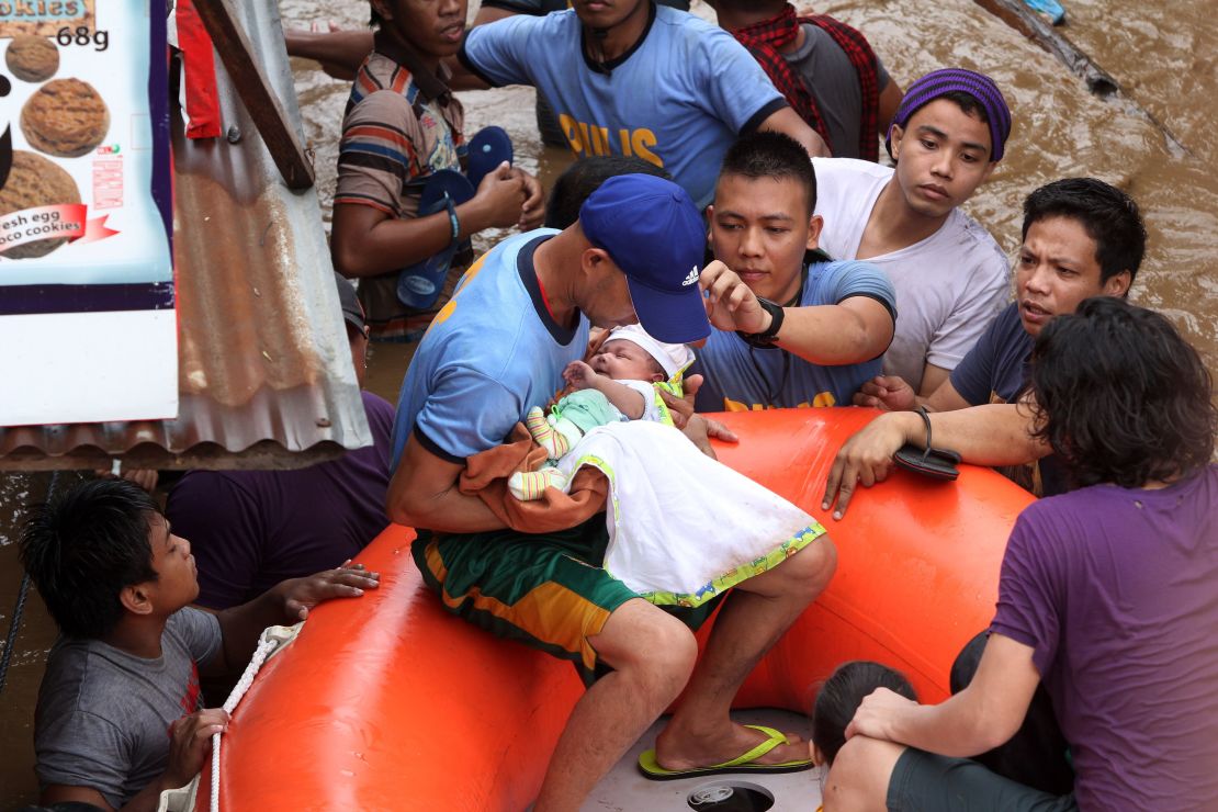 Police officers evacuate a baby Friday in Cagayan de Oro after Tropical Storm Tembin hit. 