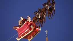  An actor dressed as Santa Claus waves from a suspended sleigh over a Christmas market as the Dom cathedral stands behind on November 25, 2013 in Berlin, Germany. Christmas markets, which traditionally sell mulled wine, stollen cake, Christmas tree ornaments and other crafts and are an essential part of German Christmas tradition, open across the country this week.