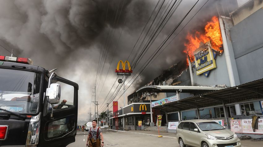 This photo taken on December 23, 2017 shows a firefighter standing in front of a burning shopping mall in Davao City on the southern Philippine island of Mindanao.