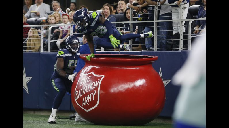 Seattle cornerback Justin Coleman jumps out of a Salvation Army kettle with defensive end Frank Clark after returning an interception for a touchdown against Dallas during an NFL game in Arlington, Texas, on Sunday, December 24. Seattle won 21-12. <br />