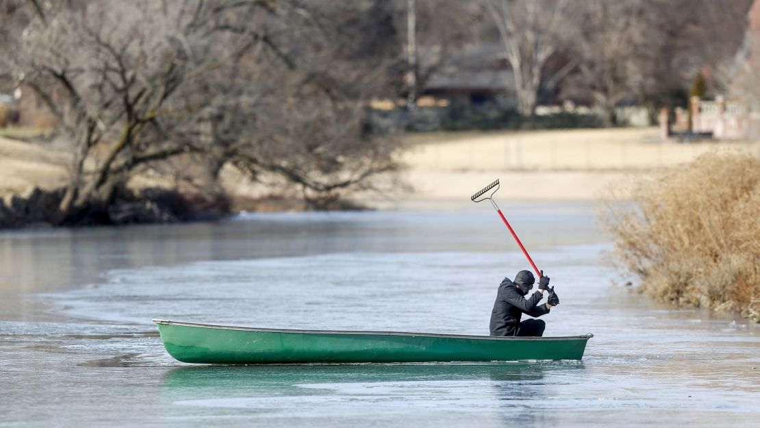 Tim Christmore uses a rake to get his canoe through the ice-covered Little Arkansas River in Wichita, Kansas.