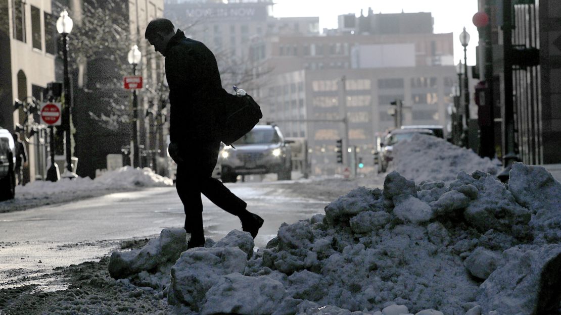 With snow on the ground, a person walks across a Boston street on Tuesday.