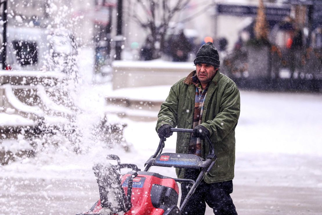 A man cleans a sidewalk with a snowplow during snowfall in Chicago on December 24.
