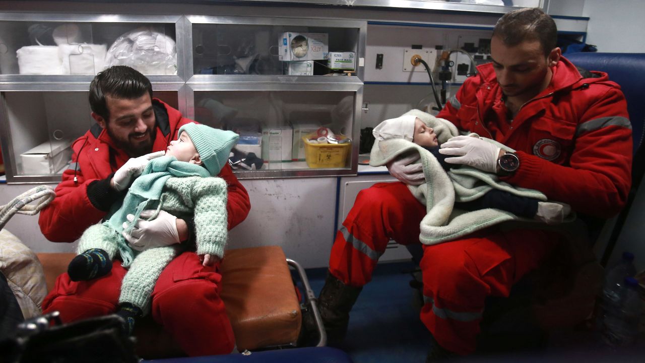 Paramedics distract children inside an ambulance on December 27, the second night of an evacuation operation led by the Syrian Red Crescent and the International Committee of the Red Cross in Douma, Syria, on the outskirts of the capital of Damascus.