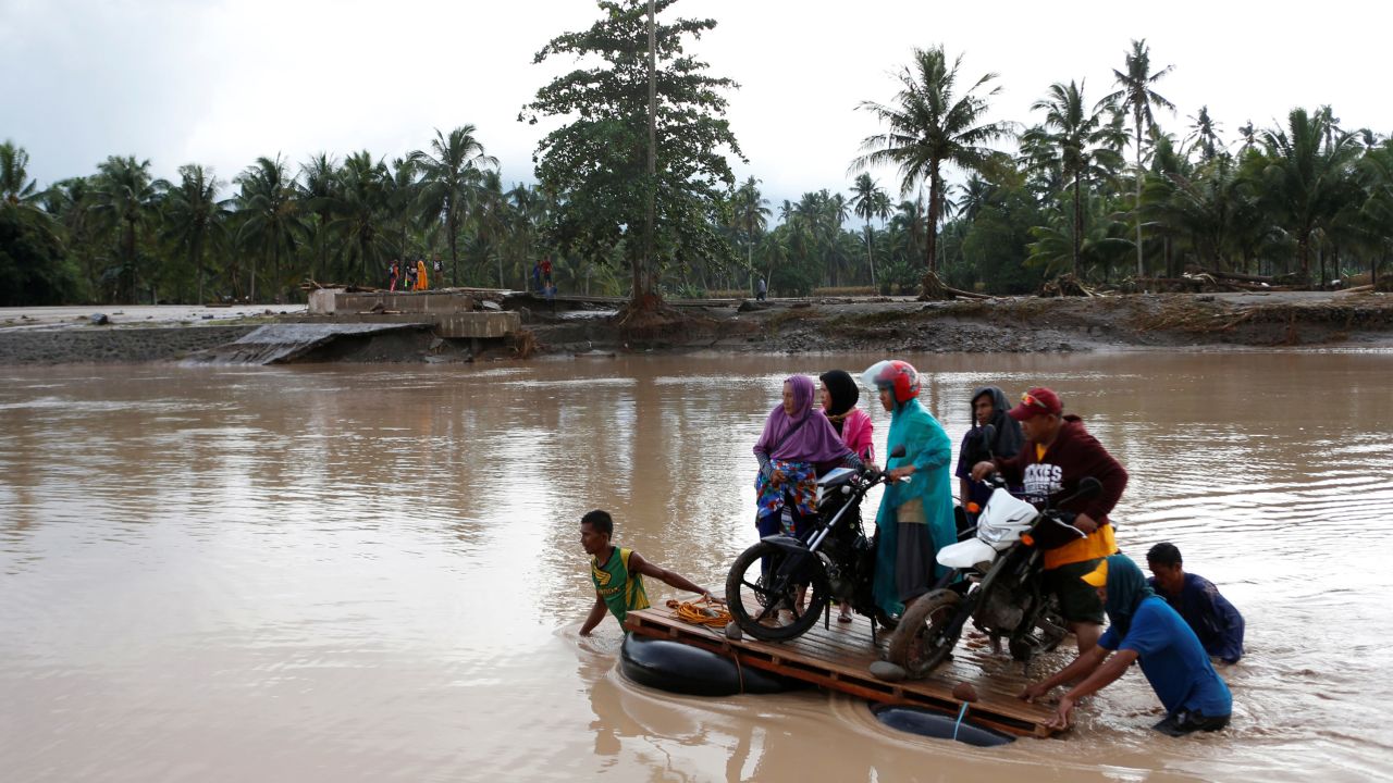 People cross a river on makeshift rafts in the flood-hit town of Salvador, Philippines, on December 23.