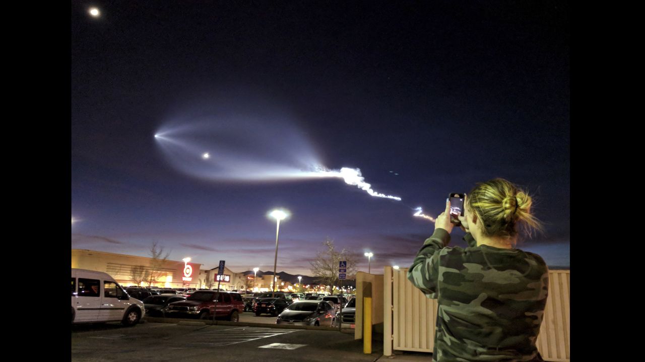 A woman photographs the light trail left behind by SpaceX's Falcon 9 rocket launch on December 22 in Apple Valley, California. The rocket took off from Vandenberg Air Force Base in central California, carrying telecommunications satellites for Iridium Communications.<br />