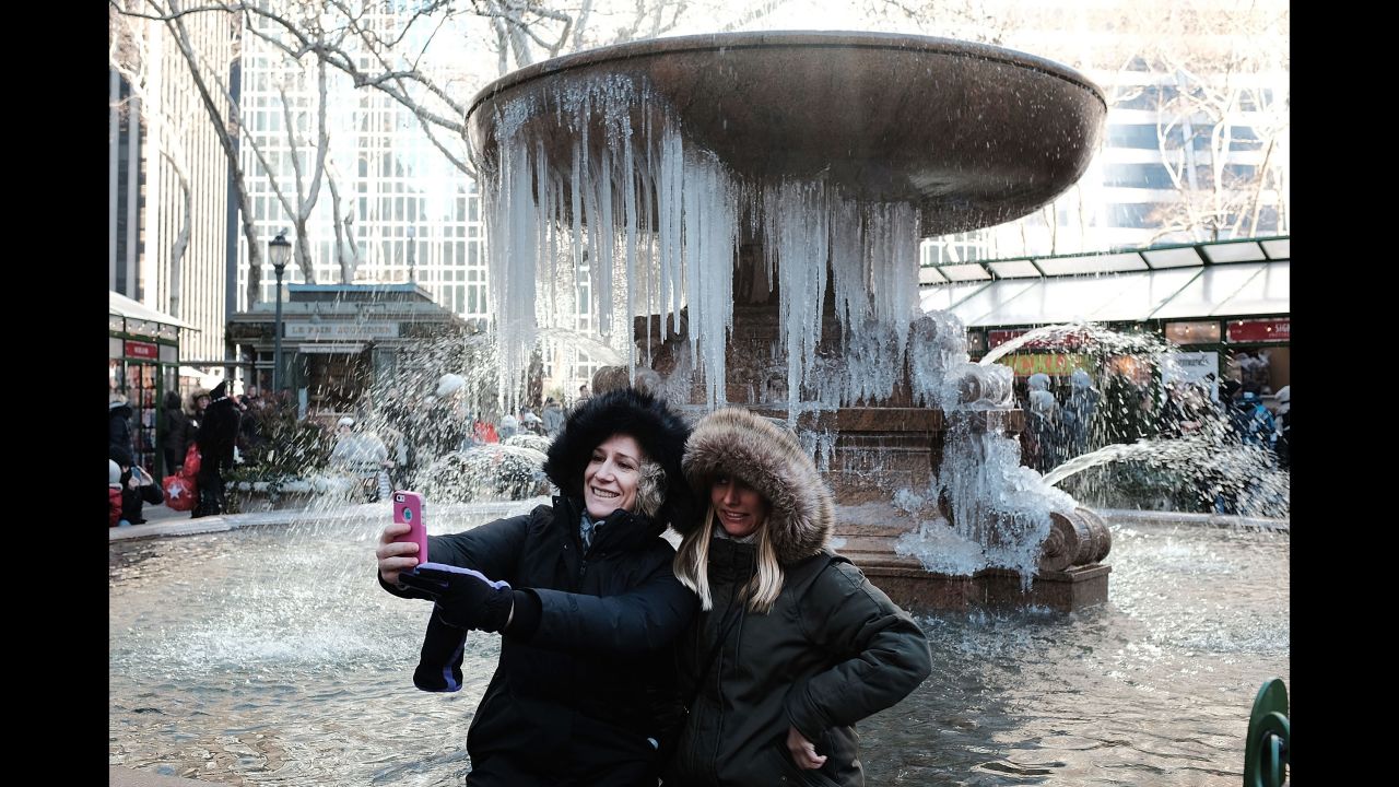 Two women take a selfie in front of a partially frozen fountain in New York City on Wednesday, December 27.
