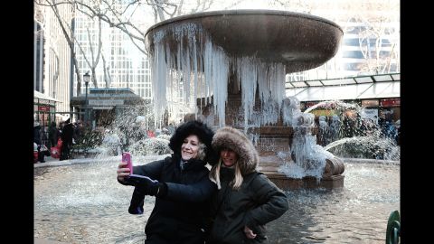 Two women take a selfie in front of a partially frozen fountain in New York City on Wednesday, December 27.