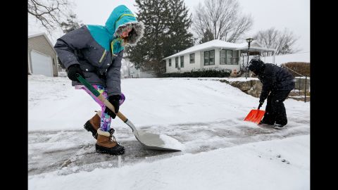 Karlee Winter and her brother Samuel Espinoza shovel snow from their neighbor's sidewalk in Dubuque, Iowa, on December 28.