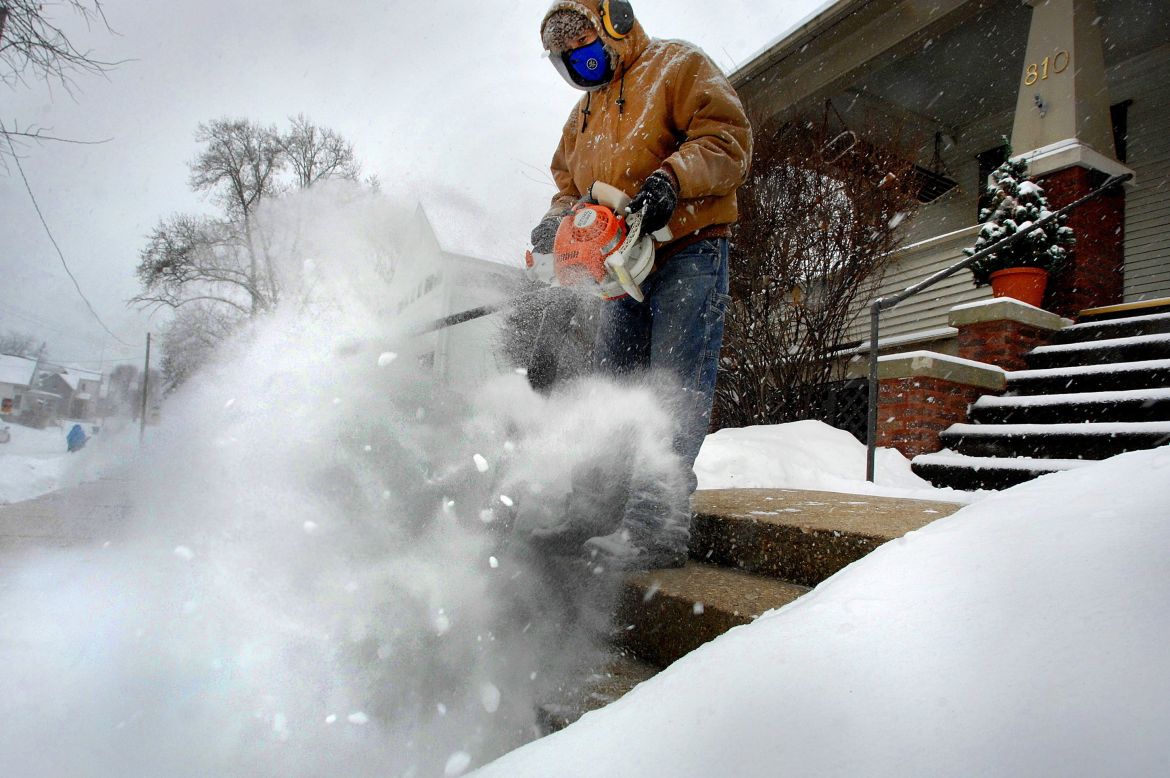 Jose Nieto uses a leaf blower to clear snow from the steps of a sick neighbor's house in Bloomington, Illinois, on December 29.