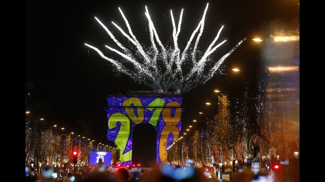 A firework explodes in Paris over the Arc de Triomphe, where spectators rang in the new year by watching images projected on the famed landmark.