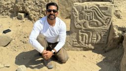 <em>Field Museum scientist Luis Muro Ynoñán with the carving of a mythological bird creature in La Otra Banda, Cerro Las Animas. Photo by the </em>