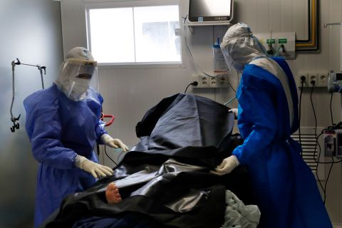 Health care workers place the body of a Covid-19 victim into a human remains pouch in an intensive care unit of the National Hospital in Itauguá, Paraguay, on March 17.