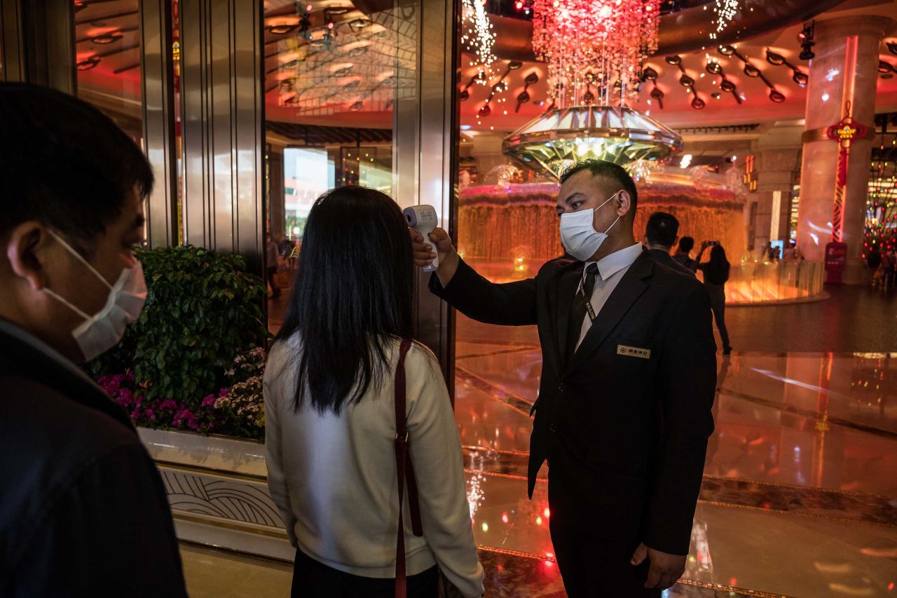 An attendant checks the temperature of a visitor at the entrance to the Galaxy Macau casino and hotel in Macau, China, on January 24.