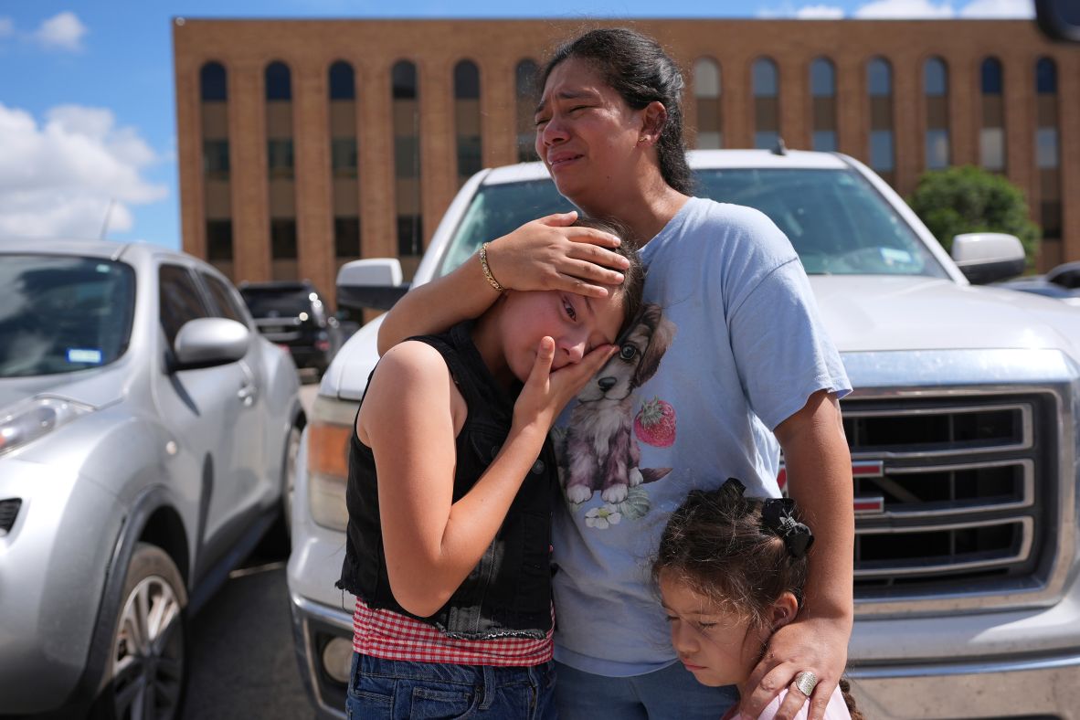 Narel Lopez comforts her daughters after her husband and a son were detained and taken away in a bus following an appearance at an immigration court in San Antonio on Wednesday, June 25.
