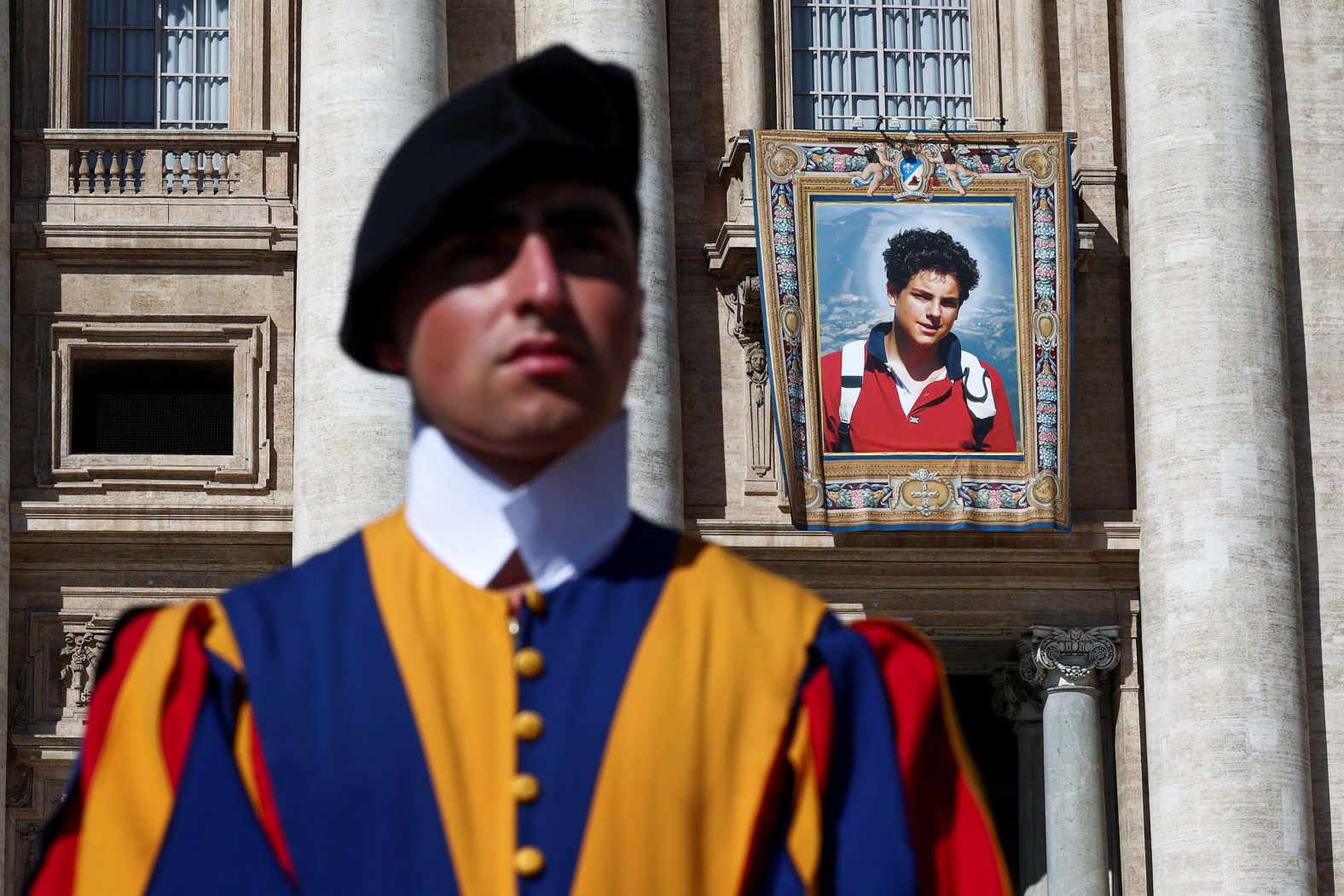 A member of the Swiss Guard stands in front of a tapestry hanging on the facade of St. Peter's Basilica at the Vatican on Saturday, September 6. The tapestry depicted Carlo Acutis, an Italian teenager <a href="index.php?page=&url=https%3A%2F%2Fwww.cnn.com%2F2025%2F09%2F07%2Feurope%2Fmillennial-saint-carlo-acutis-intl">who became the Catholic Church’s first millennial saint</a> on Sunday. Acutis was just 15 when he died from leukemia in 2006. He used his computing skills to spread awareness of the Catholic faith, setting up a website documenting reports of miracles.