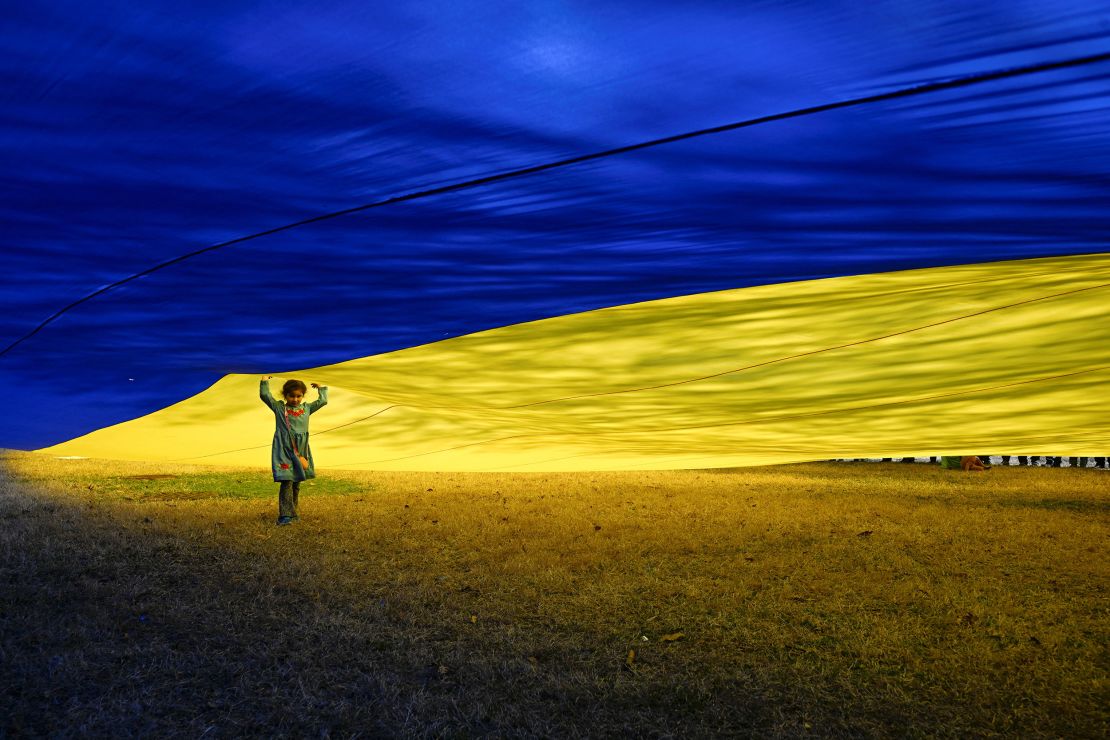 Haley Romero, 6, stands beneath a massive Ukrainian flag held by demonstrators as they rally in support of Ukraine during a protest on the Ellipse near the White House in Washington, DC, on March 8.