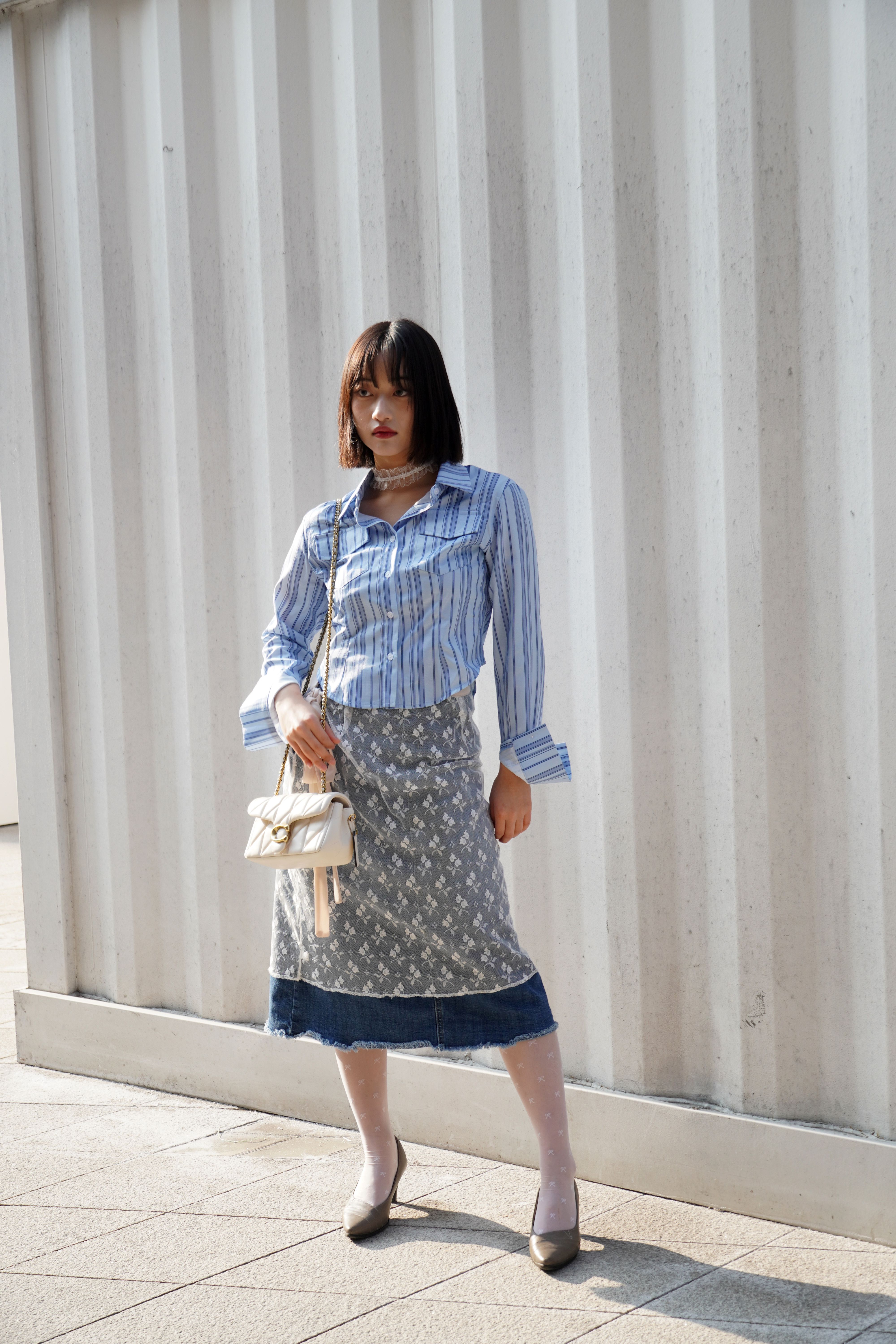 An attendees pairs her denim-trimmed skirt and striped shirt with a white lace choker.