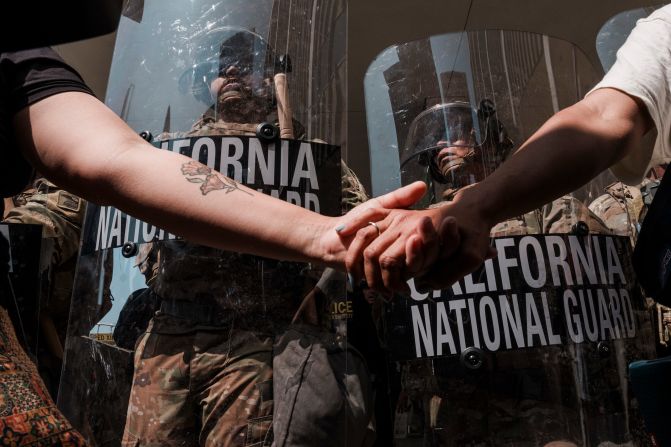 Protesters link hands near National Guard members outside a federal building in Los Angeles on Monday, June 9.