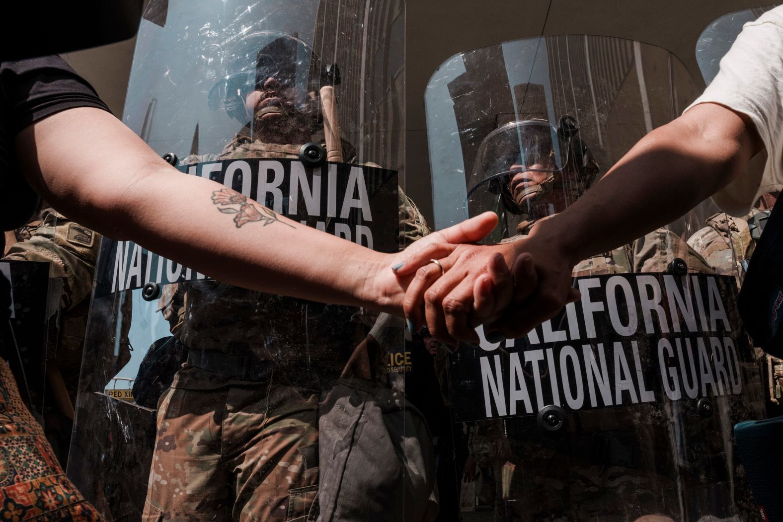 Protesters link hands near National Guard members outside a federal building in Los Angeles on Monday, June 9.