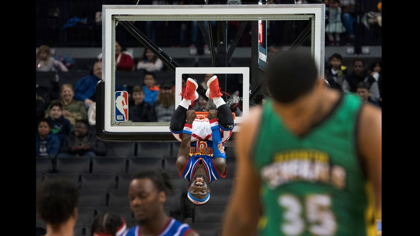Jahmani "Hot Shot" Swanson, one of the Harlem Globetrotters, hangs on the rim after a dunk in New York on Tuesday, December 26.