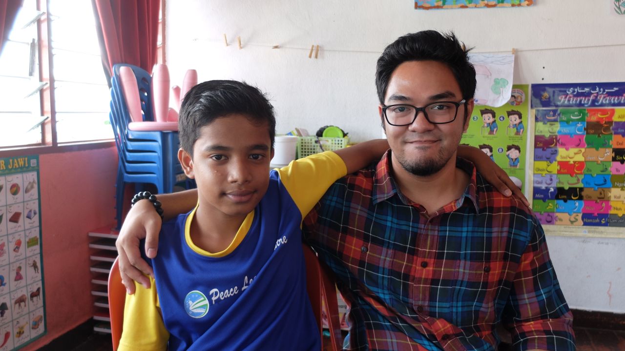 Anwar Sadek Shah Ahmad, left, sits with with volunteer teacher Haekal Kamarulzaman, 24.
