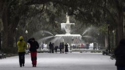 Visitors walk around the frozen fountain and snow covered sidewalks at Forsyth Park, Wednesday, Jan. 3, 2018, in Savannah, Georgia.