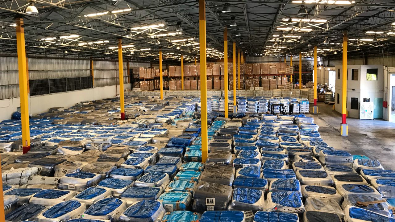 In December, 20,000 tarp rolls sit idle in a government warehouse.