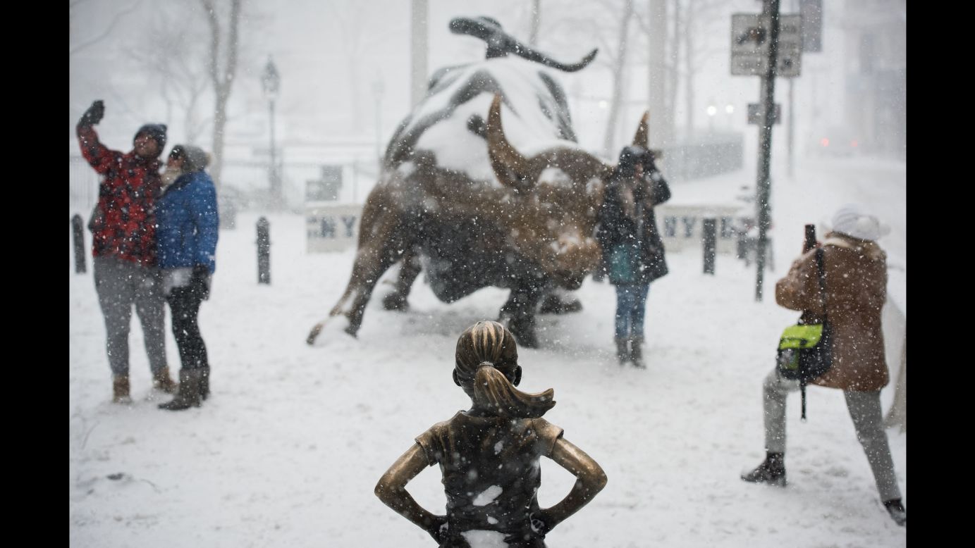 People take photos as snow falls in New York City's Financial District on Thursday, January 4.