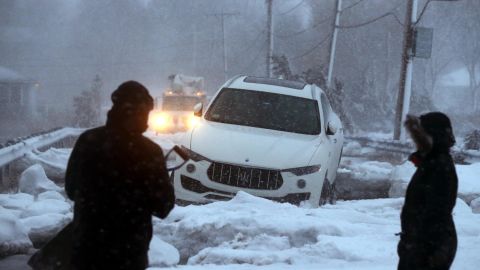 A man checks out an abandoned vehicle trapped in sea ice during the storm Thursday in Scituate.