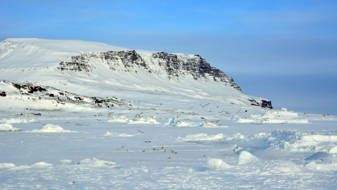 <strong>White out: </strong>In winter, Siorarsuit beach is covered by a blanket of snow, transforming the colorful island and the black surface into a landscape of pure white.
