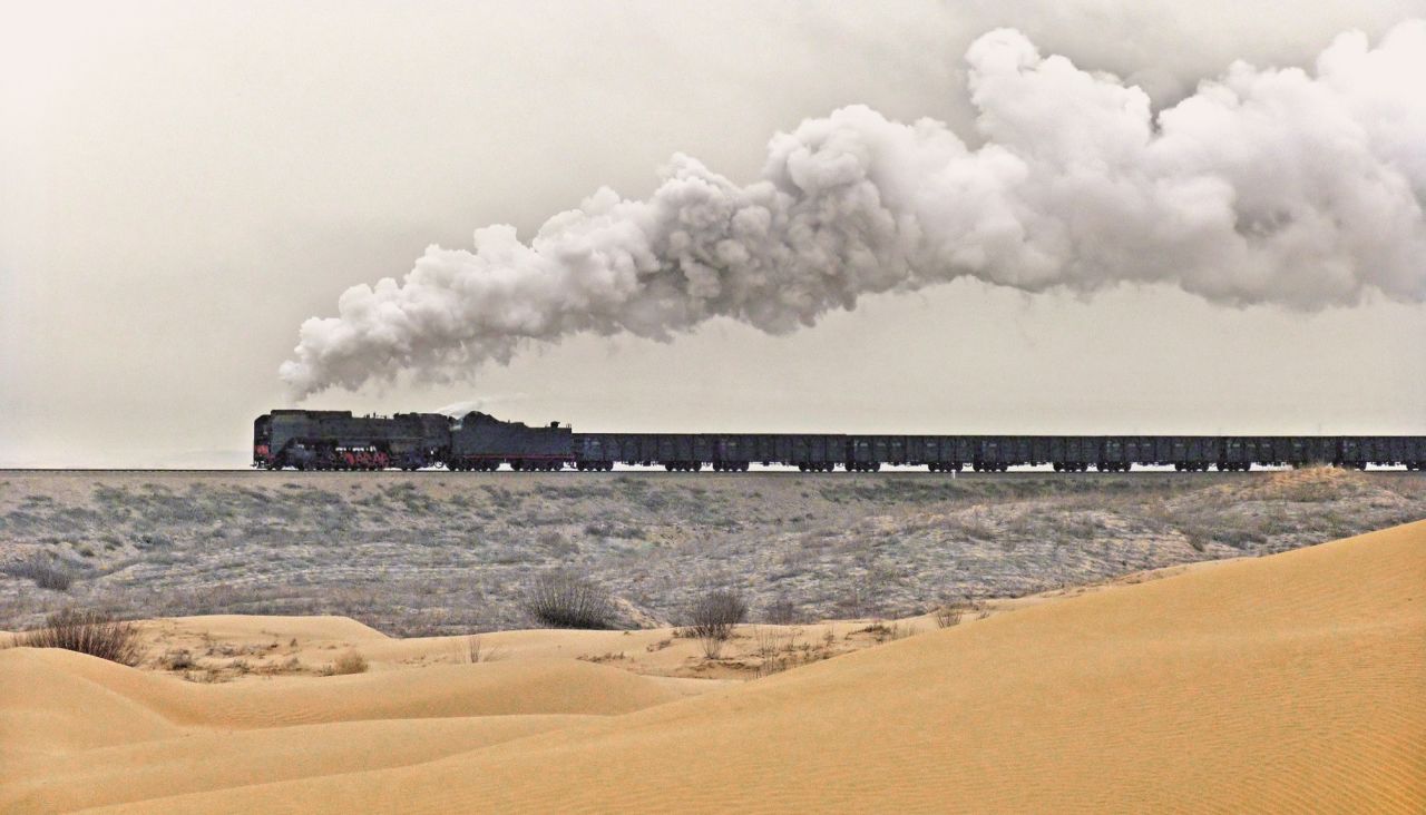 <strong>Forging connections:</strong> One memorable moment was when Kitching shared lunch with a train crew at Yuanbaoshan, in the Mongolian Autonomous Region. Pictured here: A QJ Class locomotive hauling a train through the desert to and from Guyaozi.