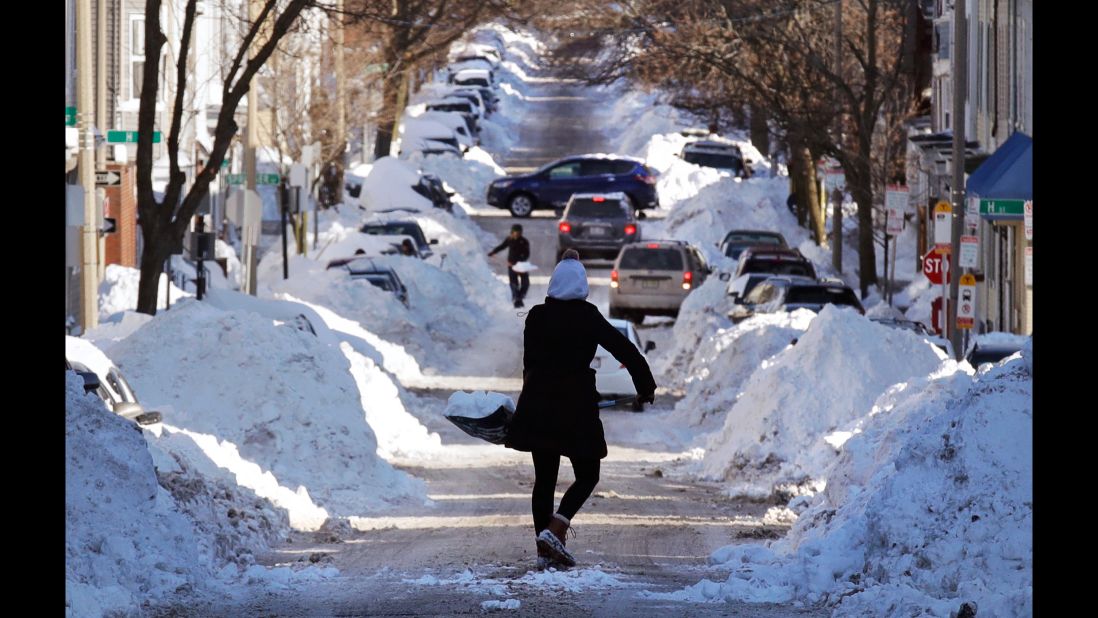Mollie Lane carries a shovelful of snow down a street while digging her car out in Boston on January 5.