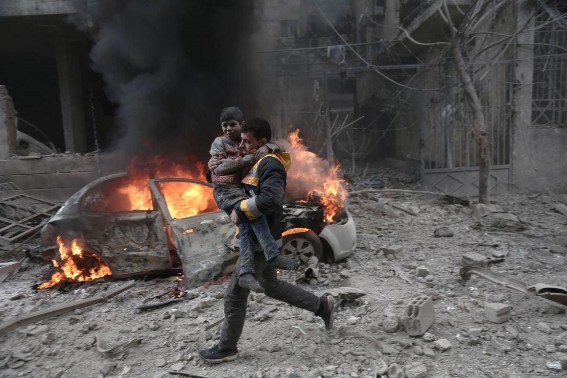 A Syrian rescuer carries an injured child following airstrikes in Eastern Ghouta on Saturday. 