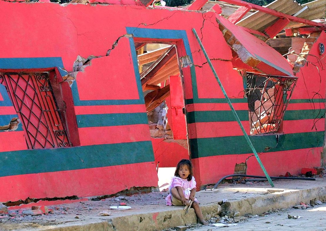 A girl sits in front of a building destroyed by the January 2001 earthquake in San Agustin, El Salvador.