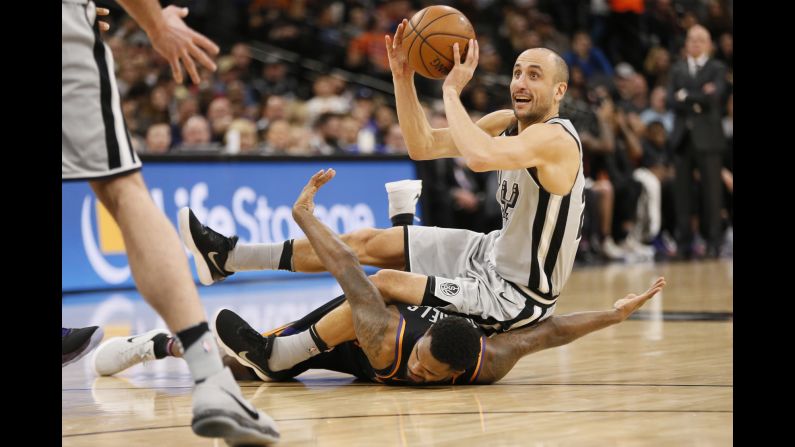 San Antonio guard Manu Ginobili looks to pass the ball as he falls over Phoenix's Troy Daniels during an NBA game on Friday, January 5.
