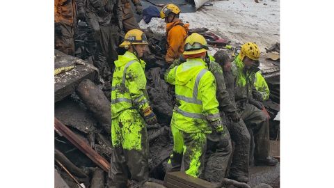 Firefighters lead a girl, 14, from the rubble where she'd been trapped for hours Tuesday in Montecito.