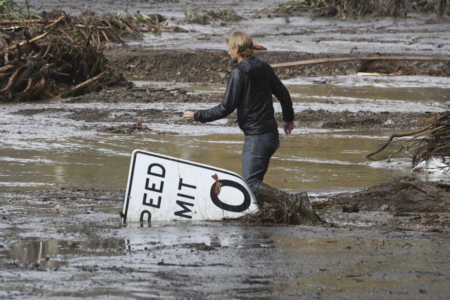 Phillip Harnsberger crosses through mud from a flooded creek in Montecito on January  9, 2018. 